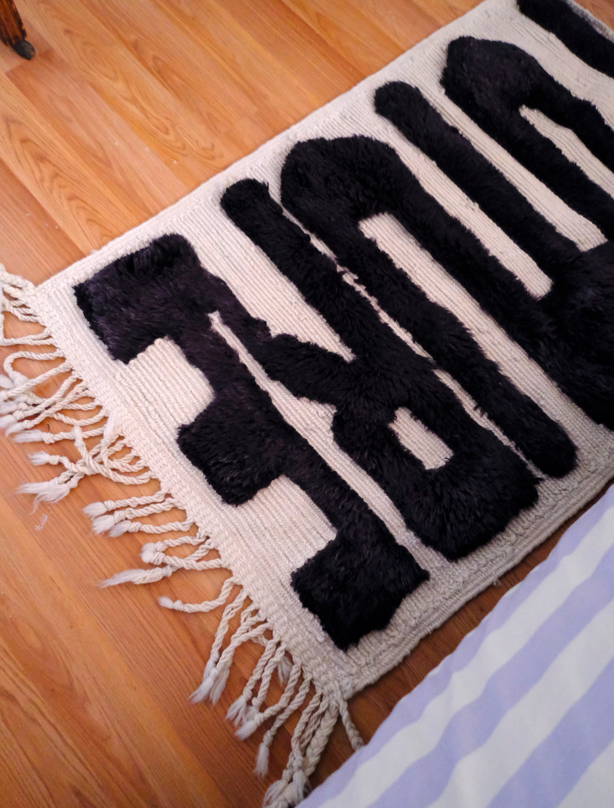 Elevate your space with the captivating "Ivory Noir Elegance Rug." Featuring embossed 'Future' letters in bold black yarn, this rug boasts a textured charm that adds a modern twist to classic black and white aesthetics. The result is a statement piece that seamlessly blends elegance and contemporary flair, making it an ideal addition to your home décor.